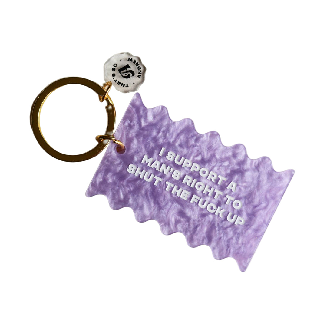 A purple, wavy acrylic keychain with white text that reads 'I SUPPORT A MAN'S RIGHT TO SHUT THE F*** UP'. 