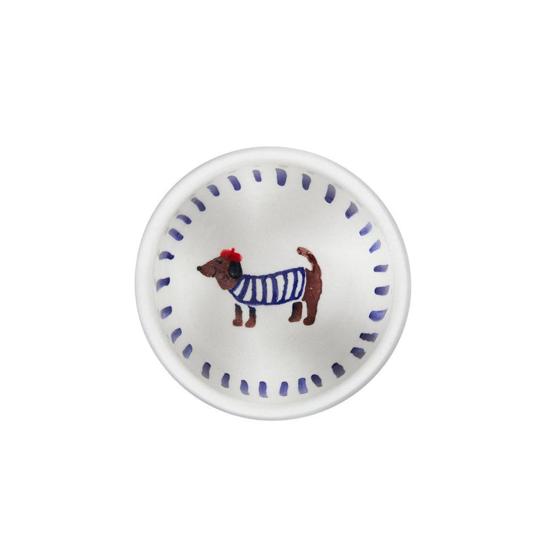 Small white plate with a dog illustration wearing a blue sweater on a white background