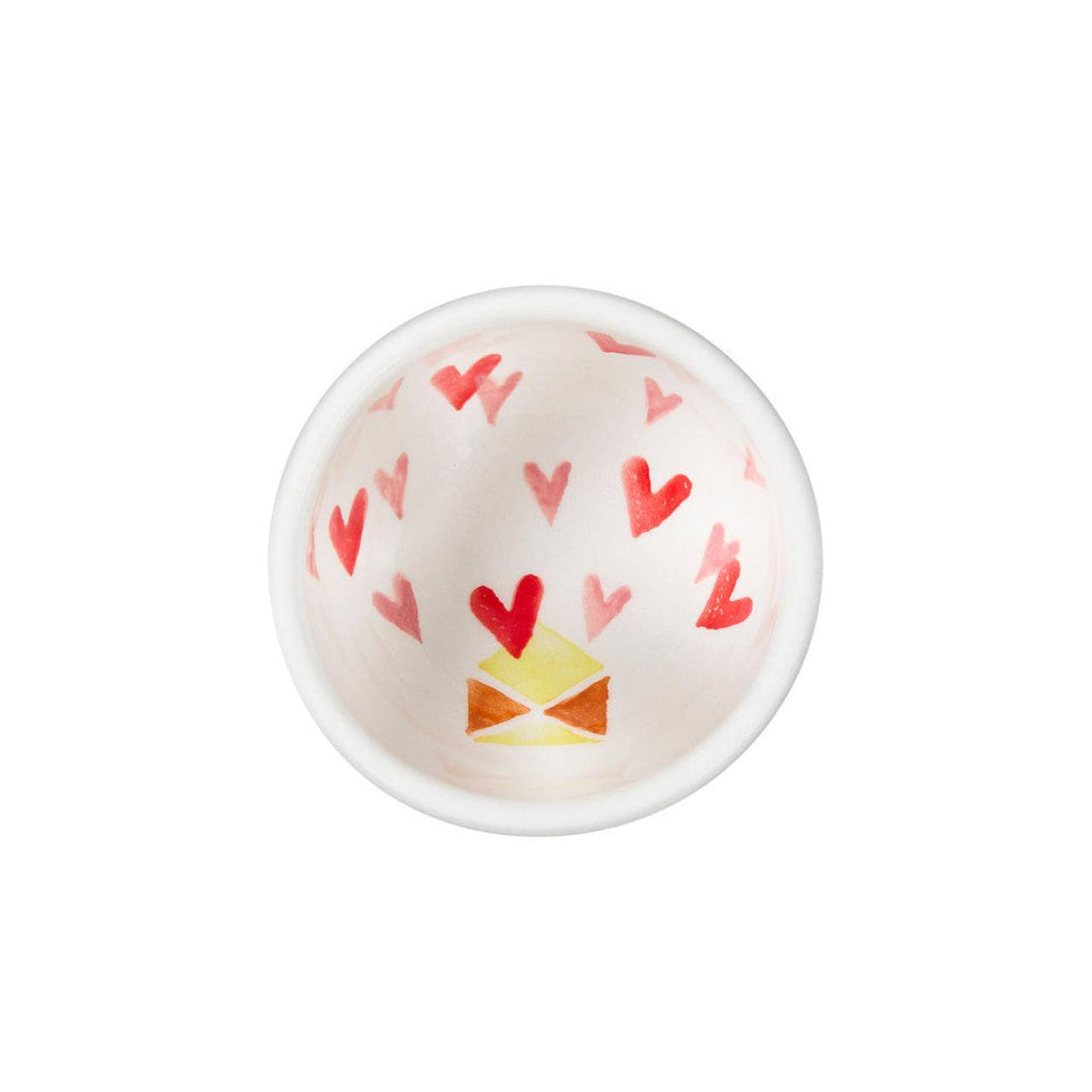 Small white bowl with red heart patterns on a white background