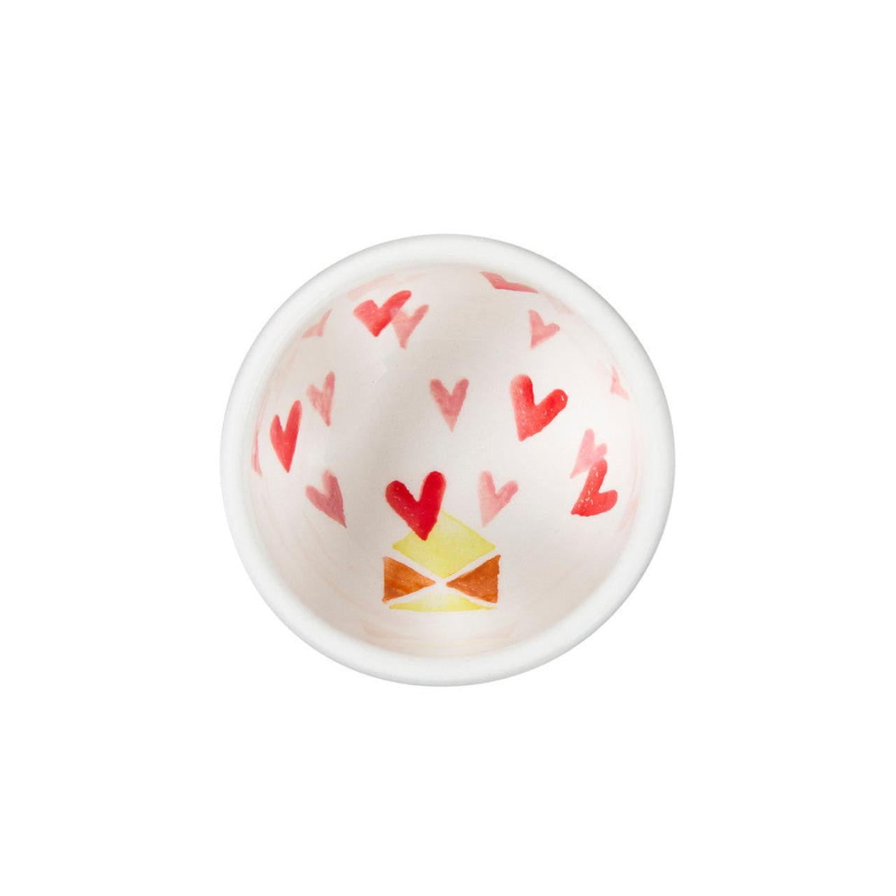 Small white bowl with red heart patterns on a white background