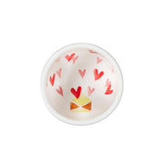 Small white bowl with red heart patterns on a white background