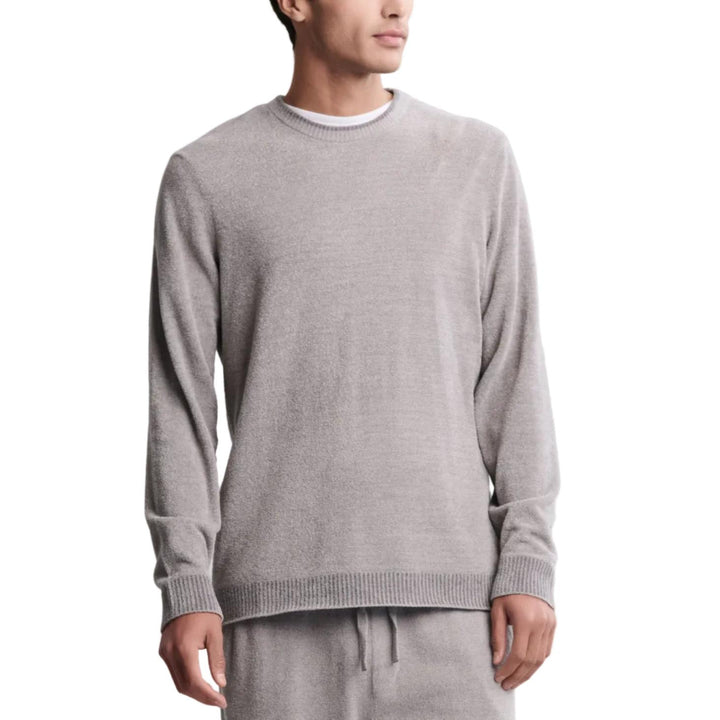 Man wearing a gray sweater and pants against a white background