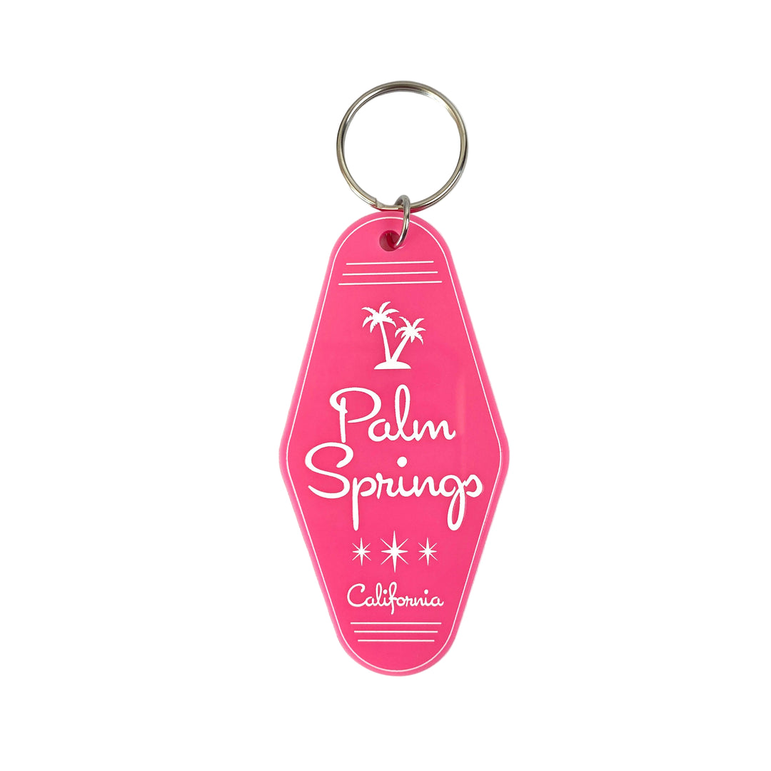 A hot pink keychain with 'Palm Springs California' embossed on it along with an illustration of two palm trees.