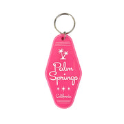 A hot pink keychain with 'Palm Springs California' embossed on it along with an illustration of two palm trees.