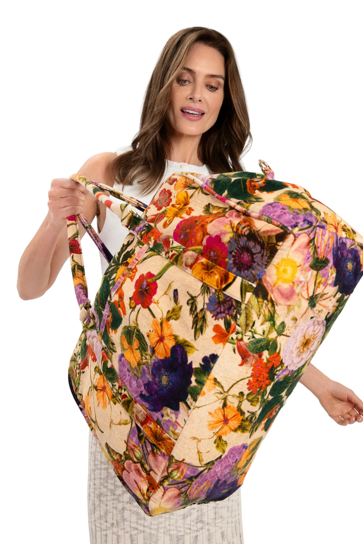 Woman holding a colorful floral-patterned bag against a white background