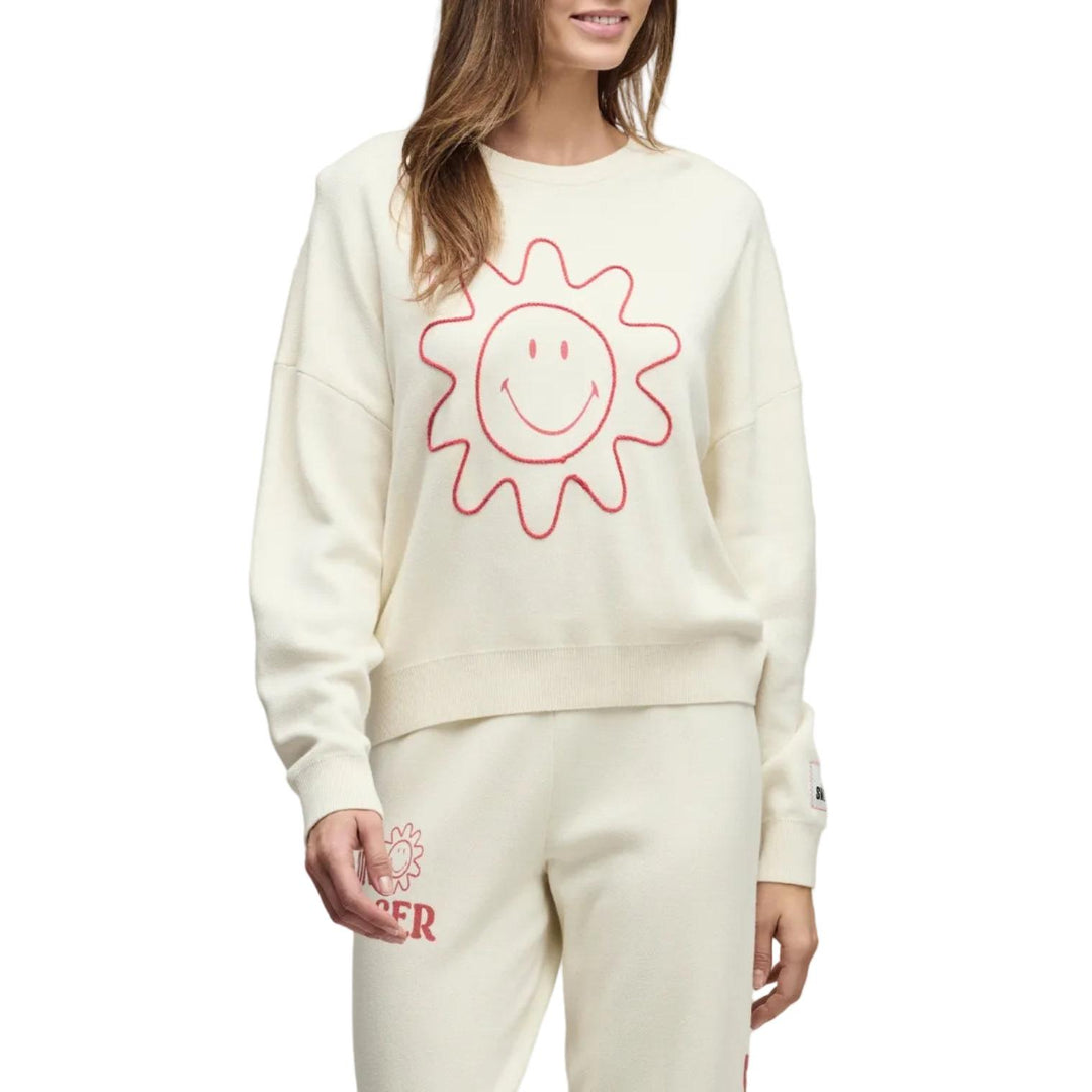 Woman wearing a cream-colored sweatshirt with a sun design on a plain background
