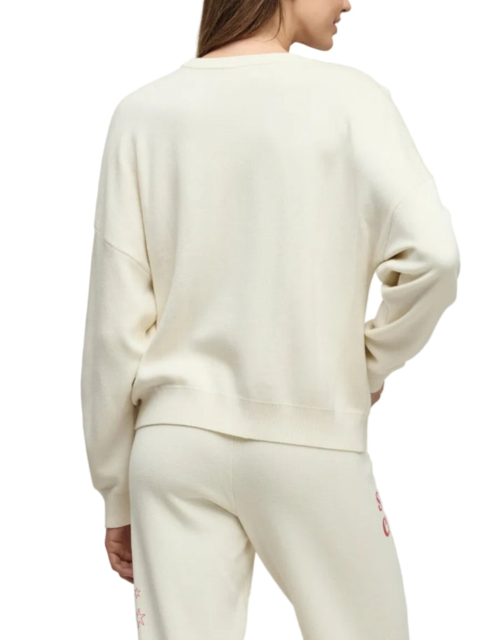 Woman wearing a cream-colored outfit against a plain background